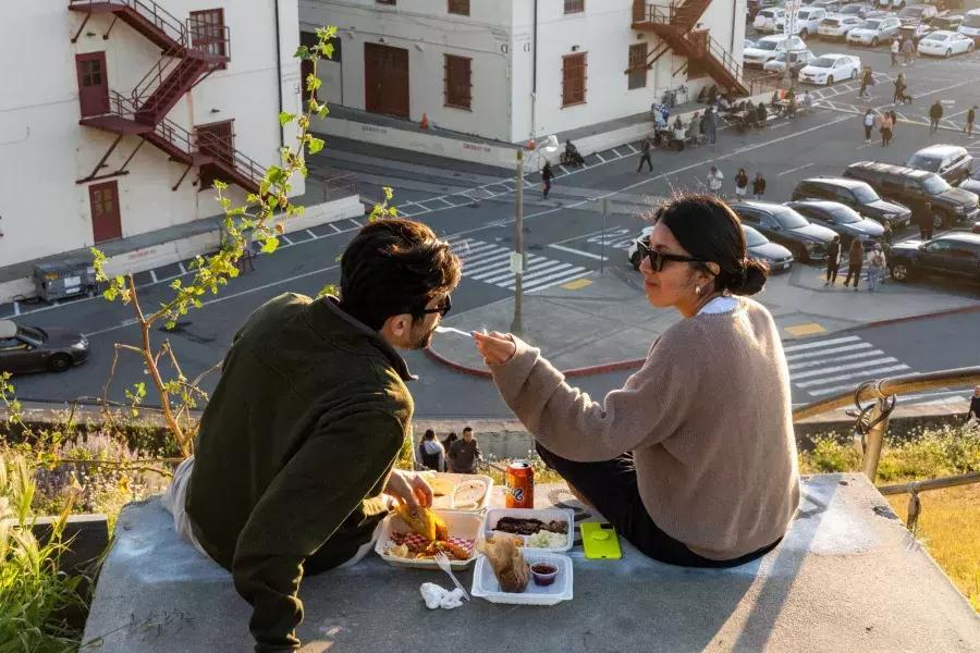 这对夫妇在贝博体彩app梅森堡中心的户外用餐。. 女人用品尝的方式喂她的同伴.